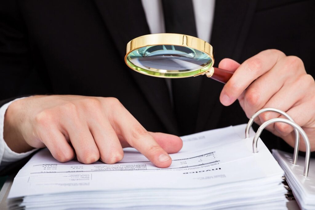 Man Inspecting Financial Documents for Compliance