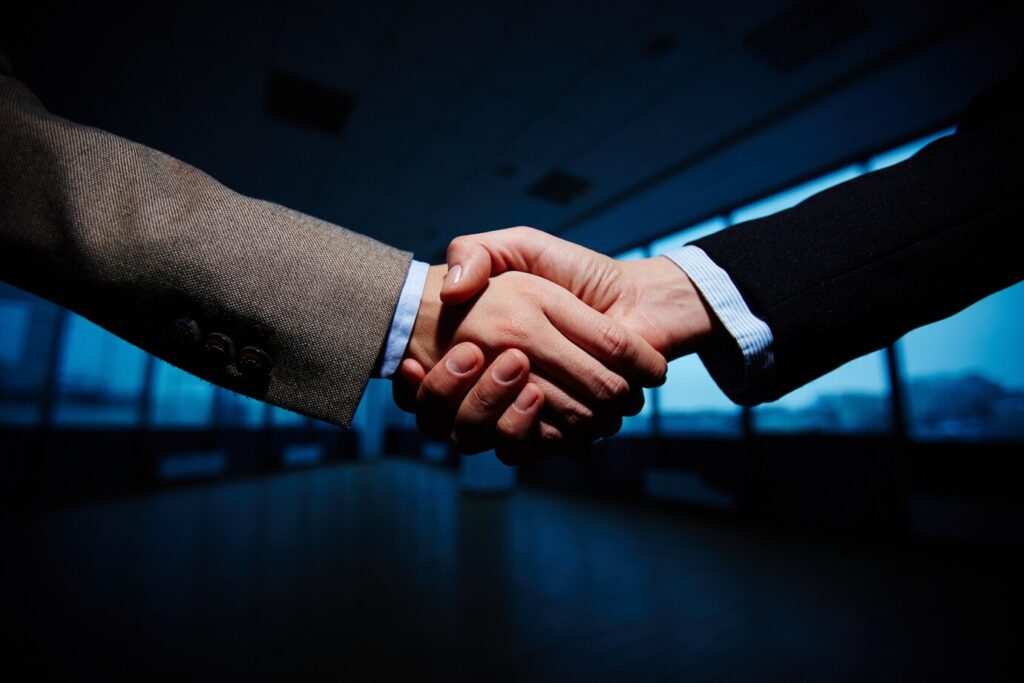 Two professionals shaking hands, symbolizing a limited partnership agreement.