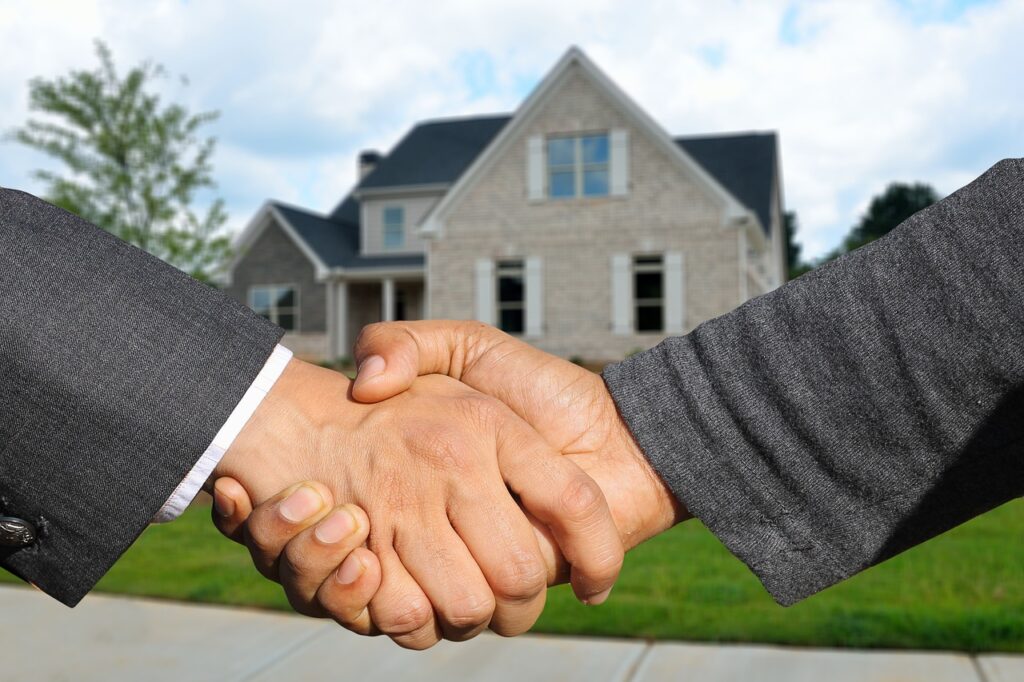 Two business partners shaking hands in front of a modern office building, symbolizing a real estate investment trust collaboration